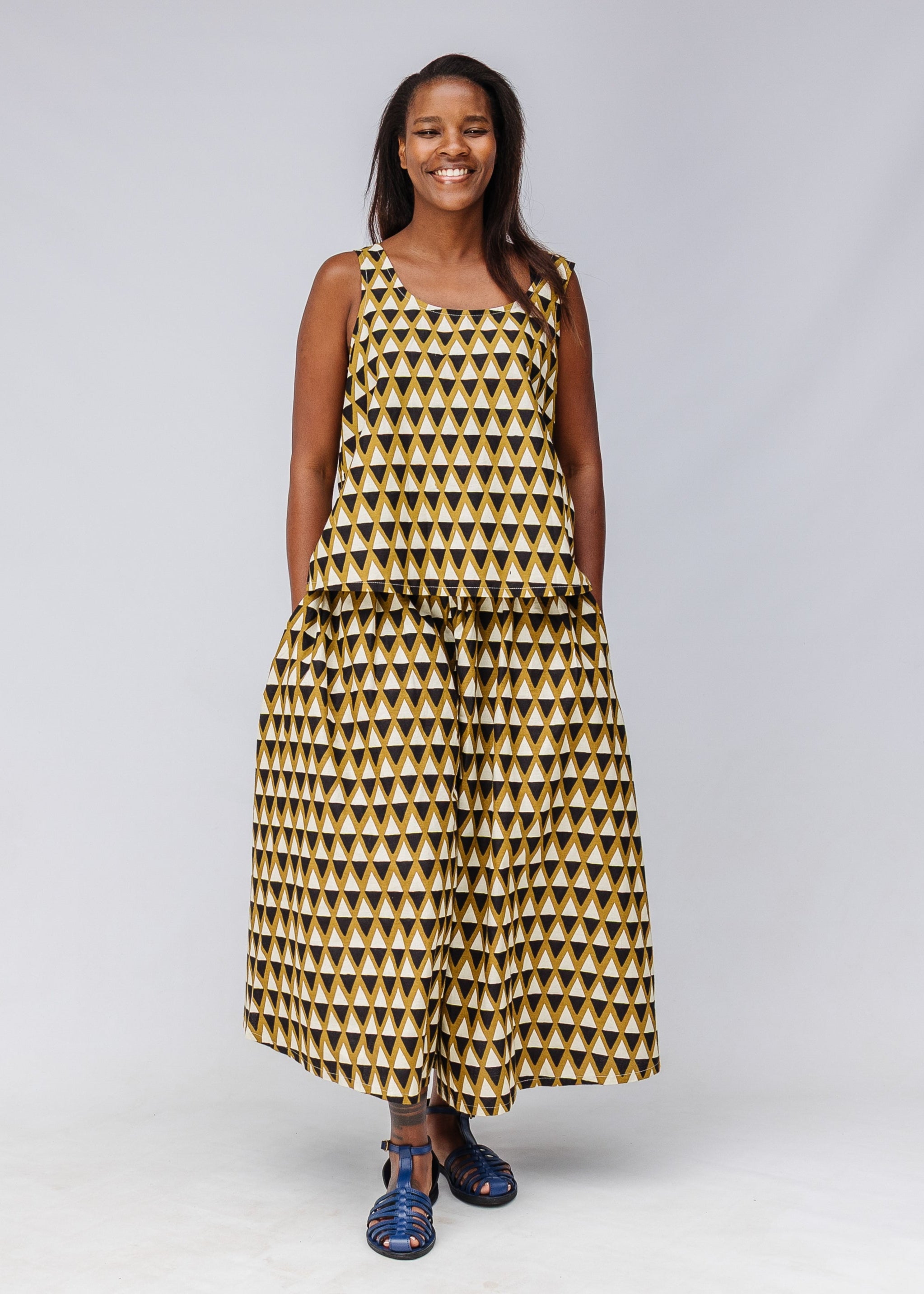 Model wearing mustard and black triangle print pants and tank.
