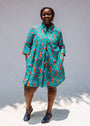 Model wearing teal dress with pink and orange shrimp print.