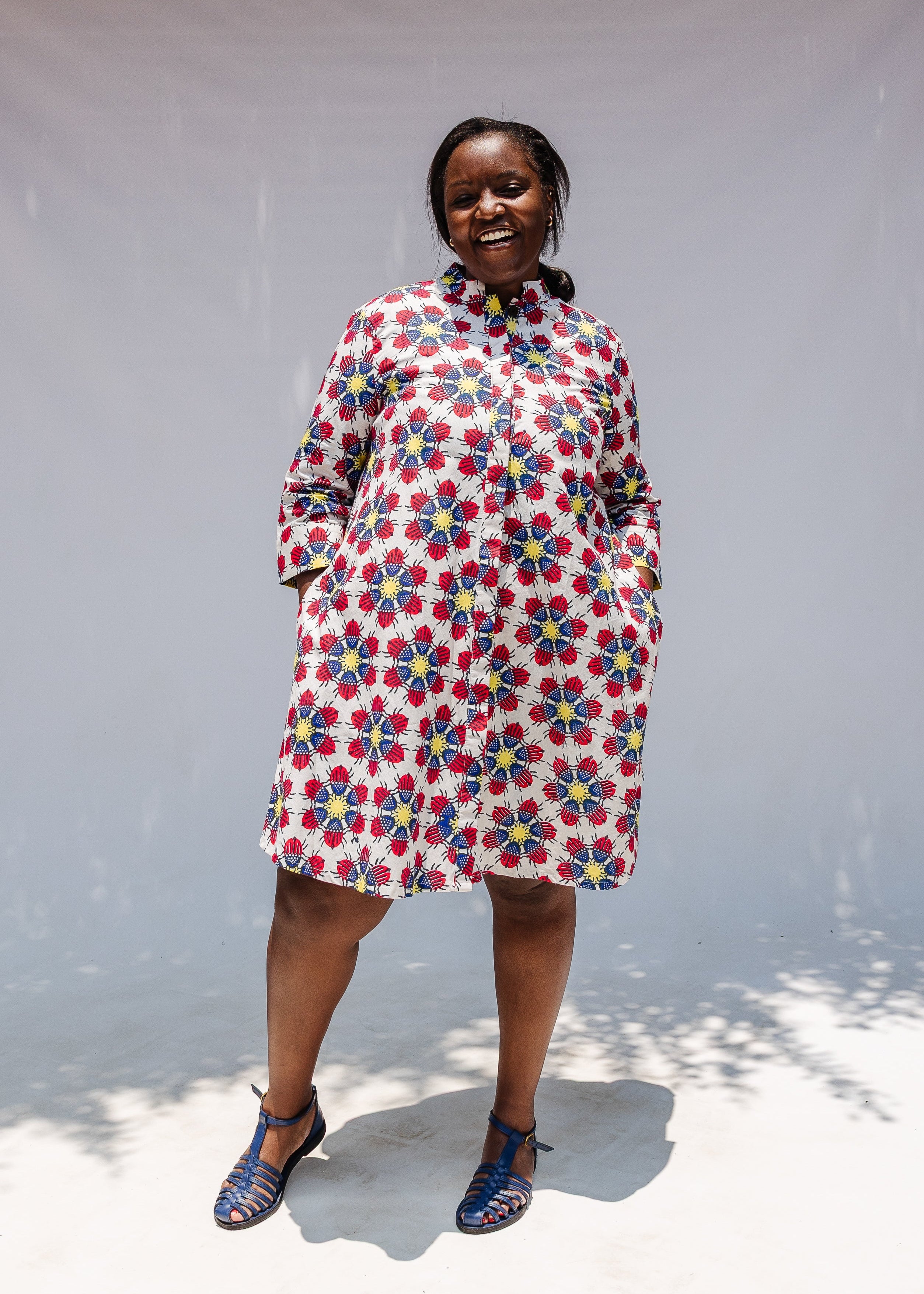 Model wearing white dress with yellow, red and blue bug print.