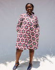 Model wearing white dress with yellow, red and blue bug print.