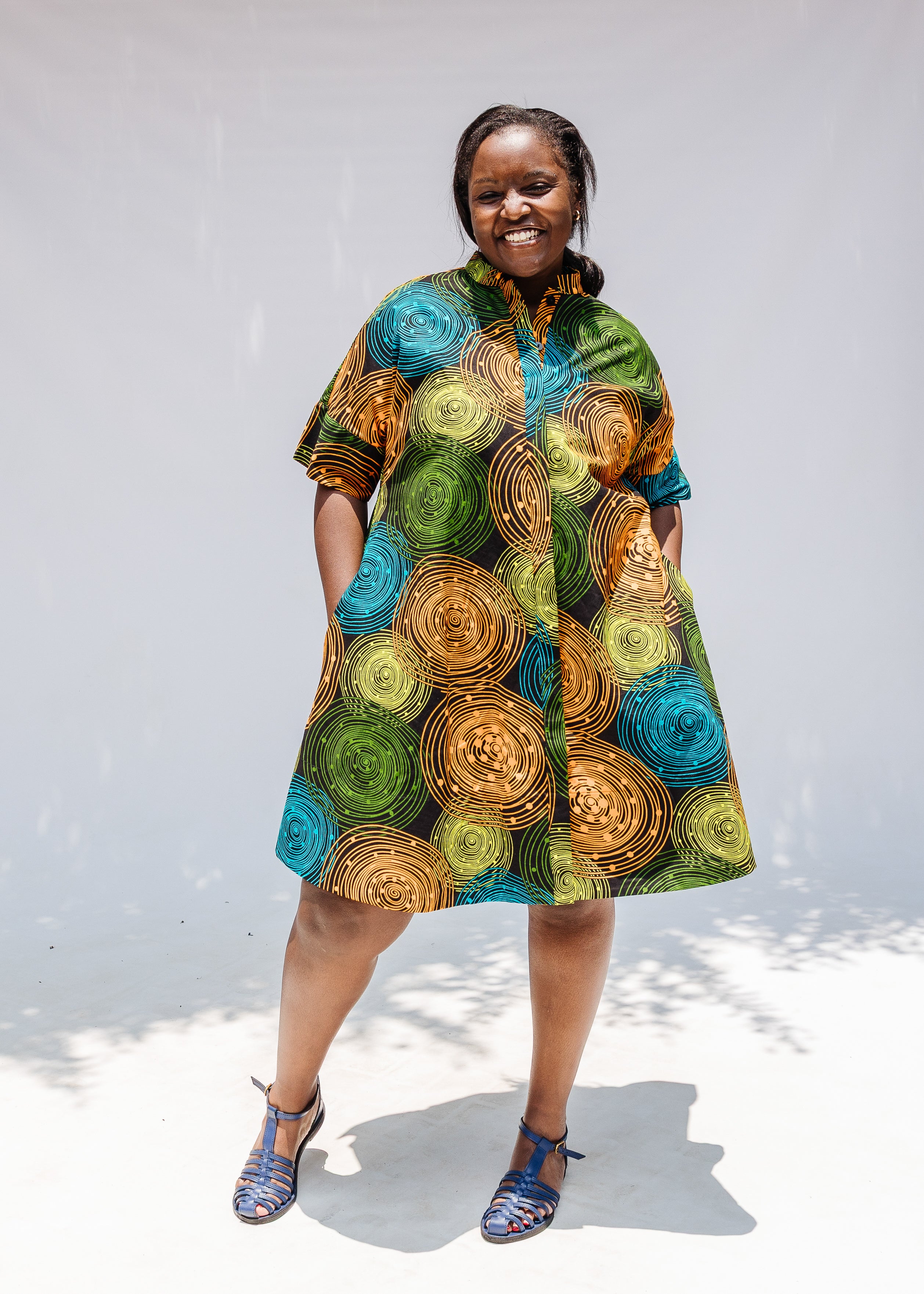 Model wearing black dress with orange, yellow, blue and green swirls.
