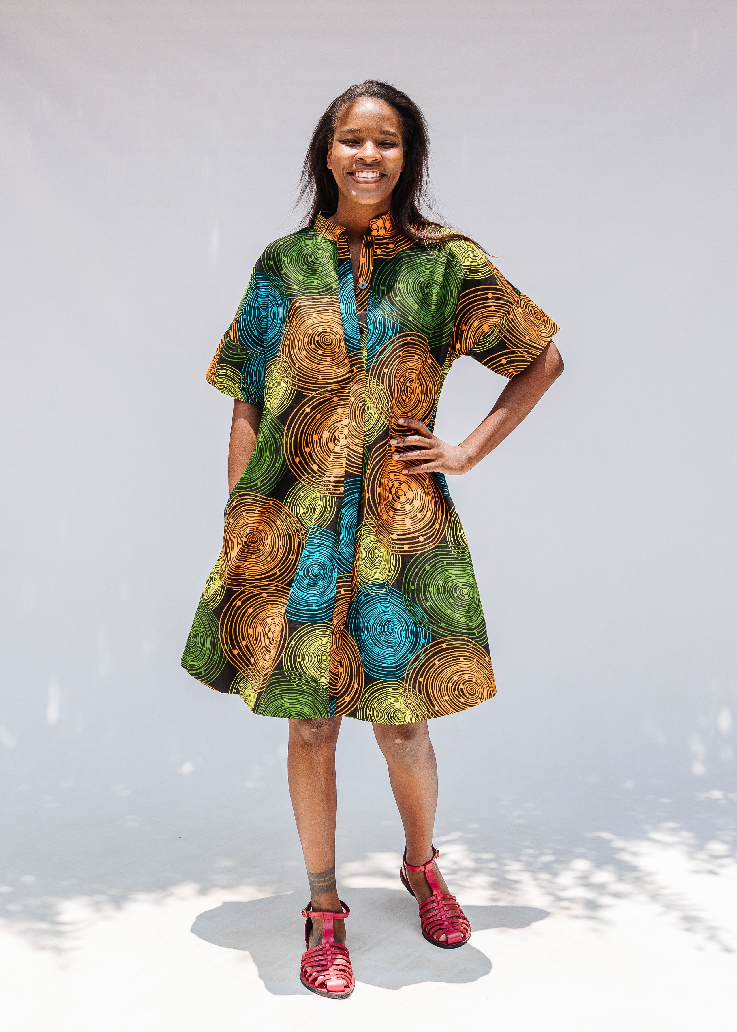 Model wearing black dress with orange, yellow, blue and green swirls.