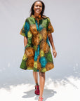 Model wearing black dress with orange, yellow, blue and green swirls.