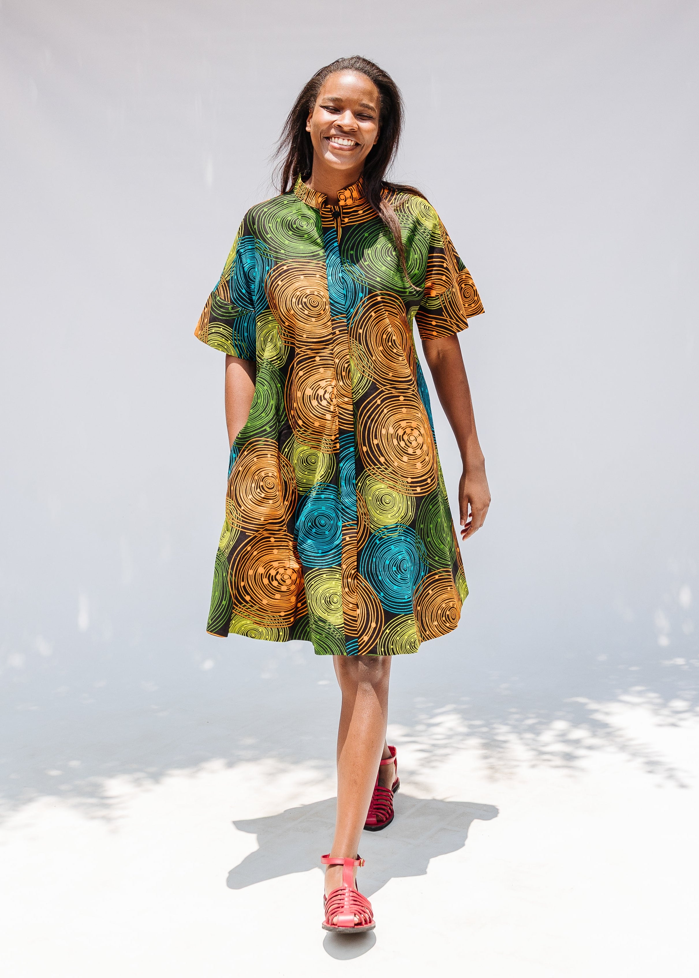 Model wearing black dress with orange, yellow, blue and green swirls.