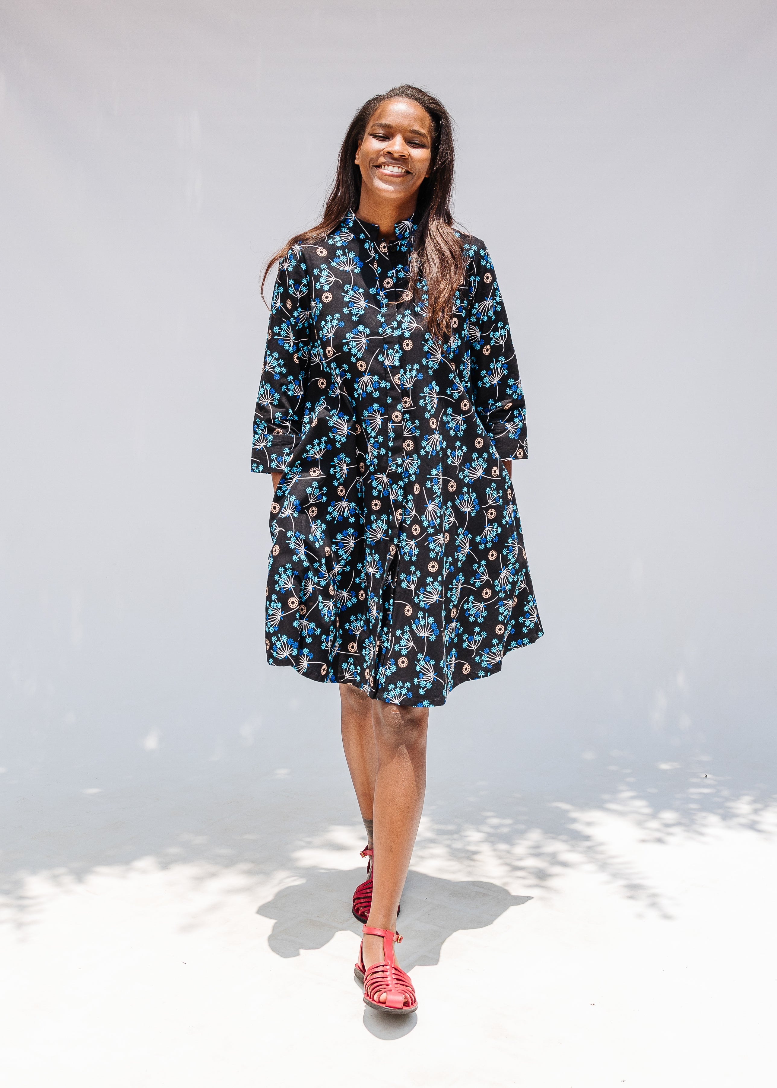 Model wearing black dress with blue and beige floral print.