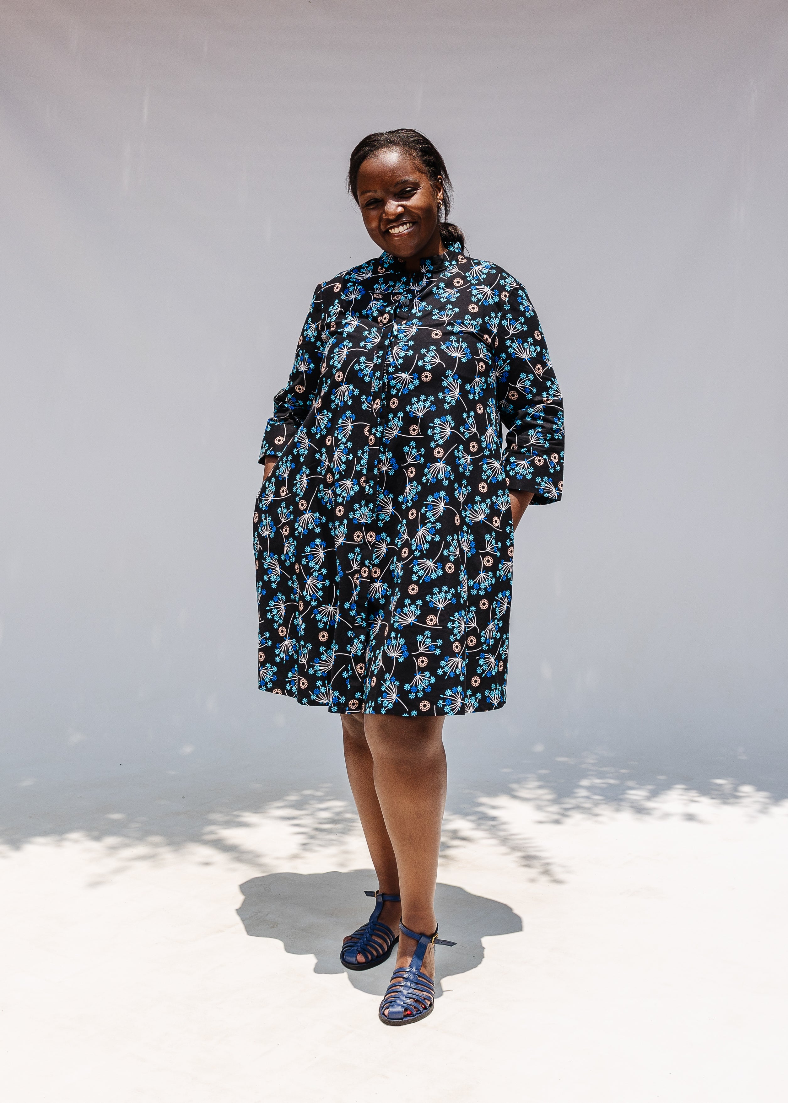 Model wearing black dress with blue and beige floral print.