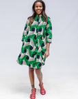 Model wearing green, black and white abstract print dress. 