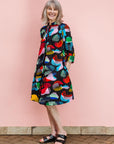 The model is wearing abstract multi-color  figures dress