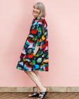 The model is wearing abstract multi-color  figures dress