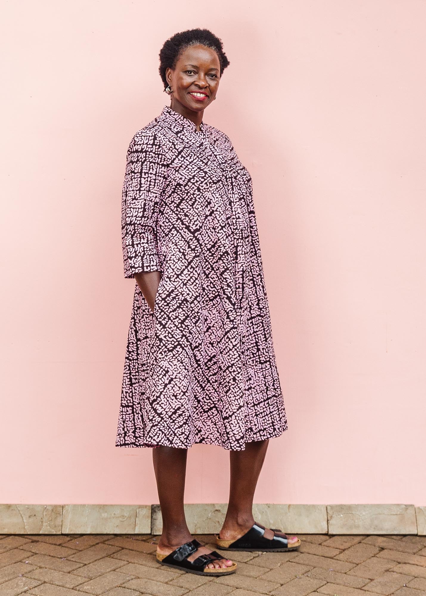 The model is wearing brown and baby pink abstract print dress