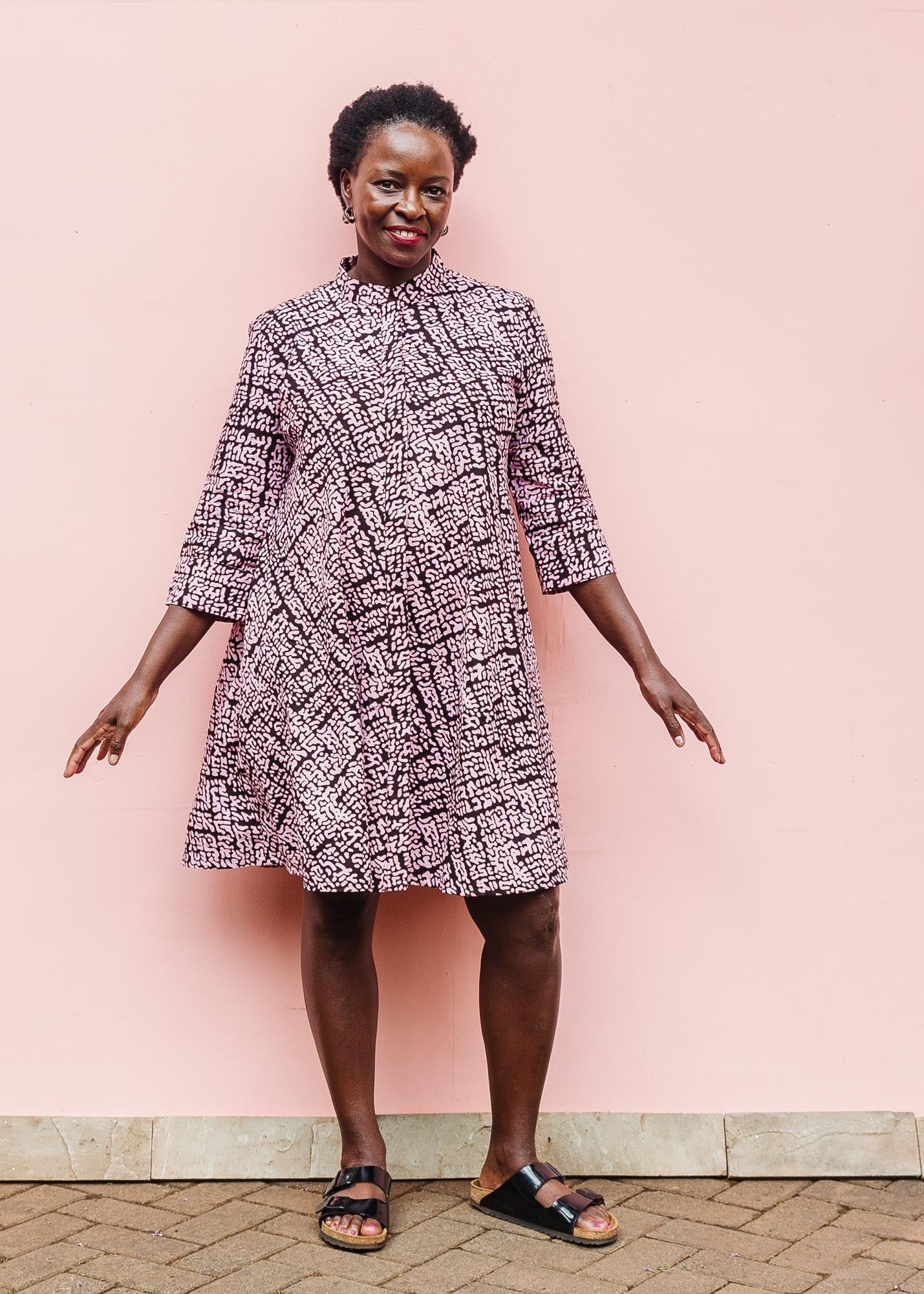 The model is wearing brown and baby pink abstract print dress