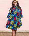 The model is wearing blue, red, yellow, black and aqua vine print dress