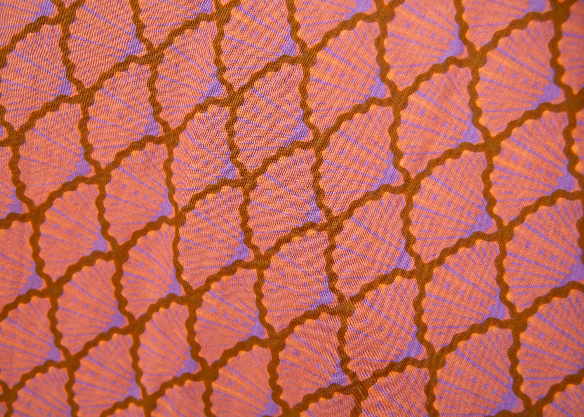 Close up display of peach-pink, lavender and brown seashell print dress