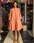 The model is wearing peach-pink, lavender and brown seashell print dress