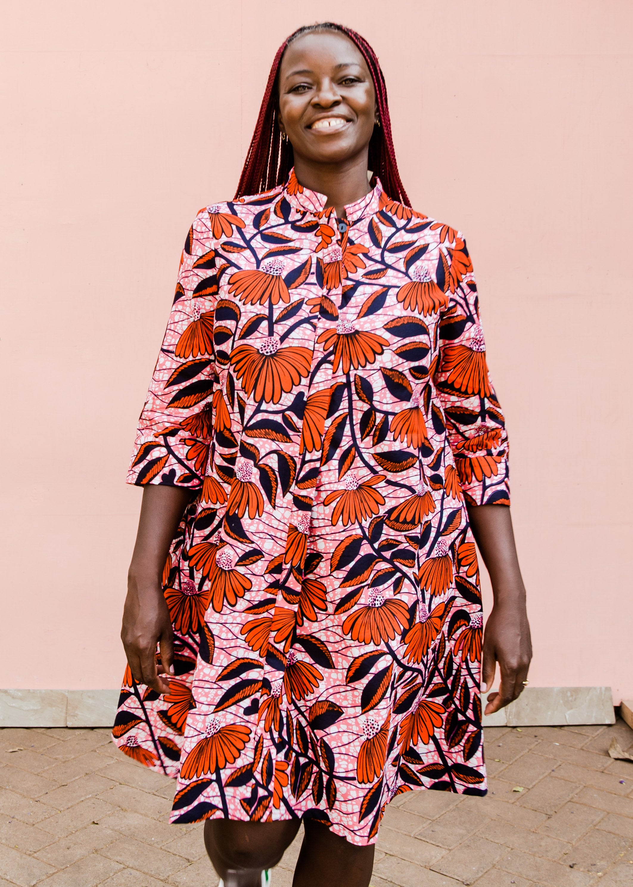 Model wearing pink dress with red and black flowers.