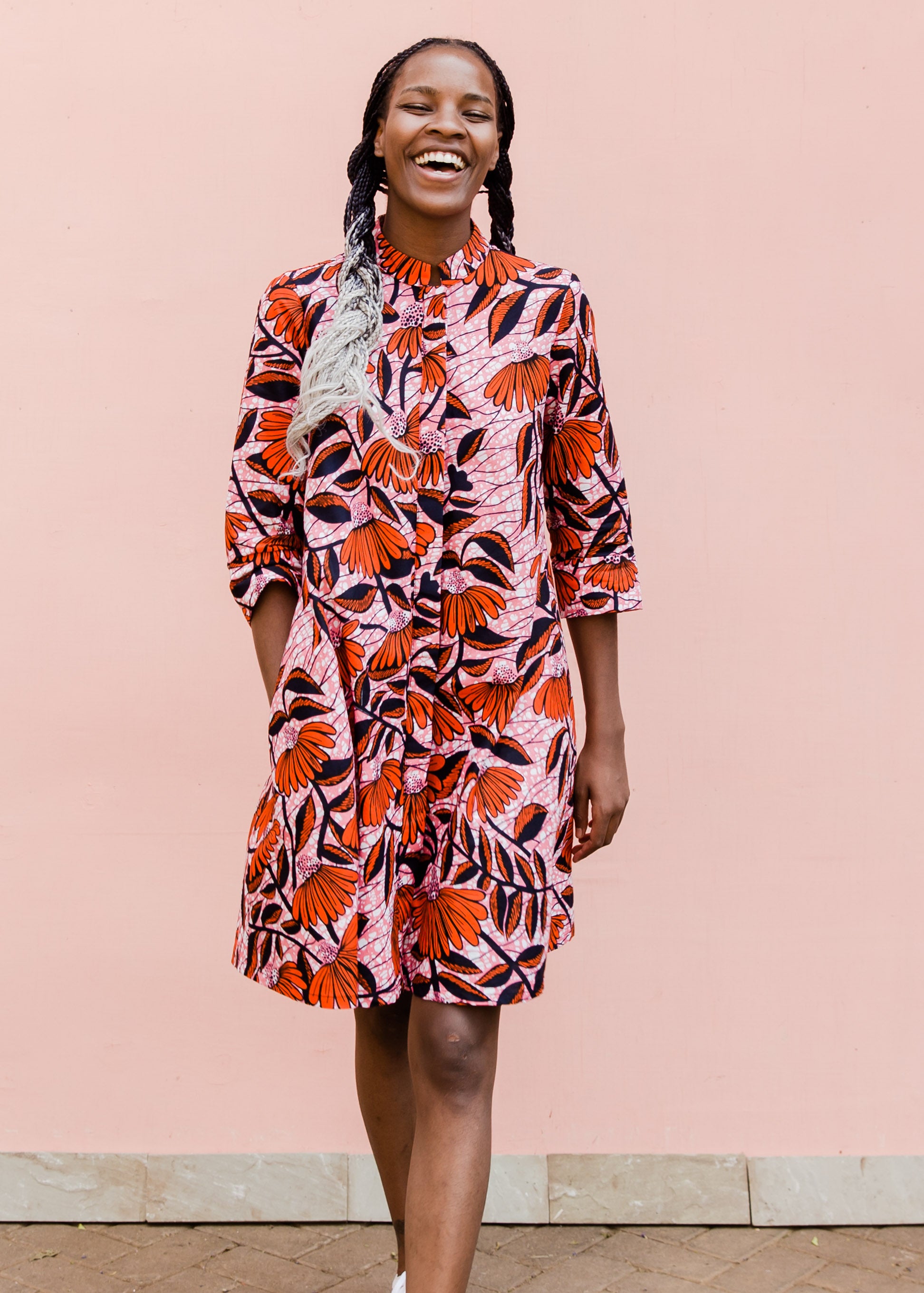 Model wearing pink dress with red and black flowers.