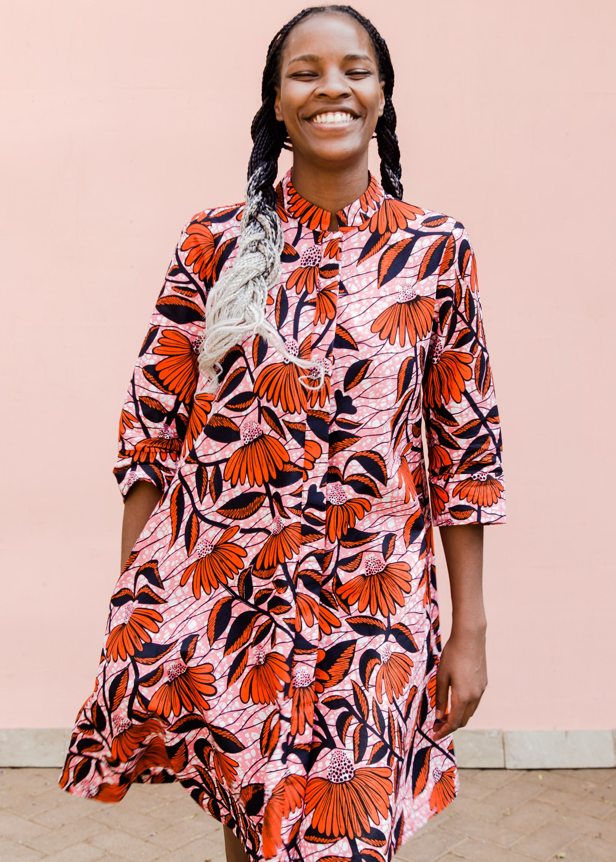 Model wearing pink dress with red and black flowers.