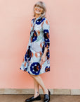 Model wearing dress with blue, green and orange abstract circular design pattern.