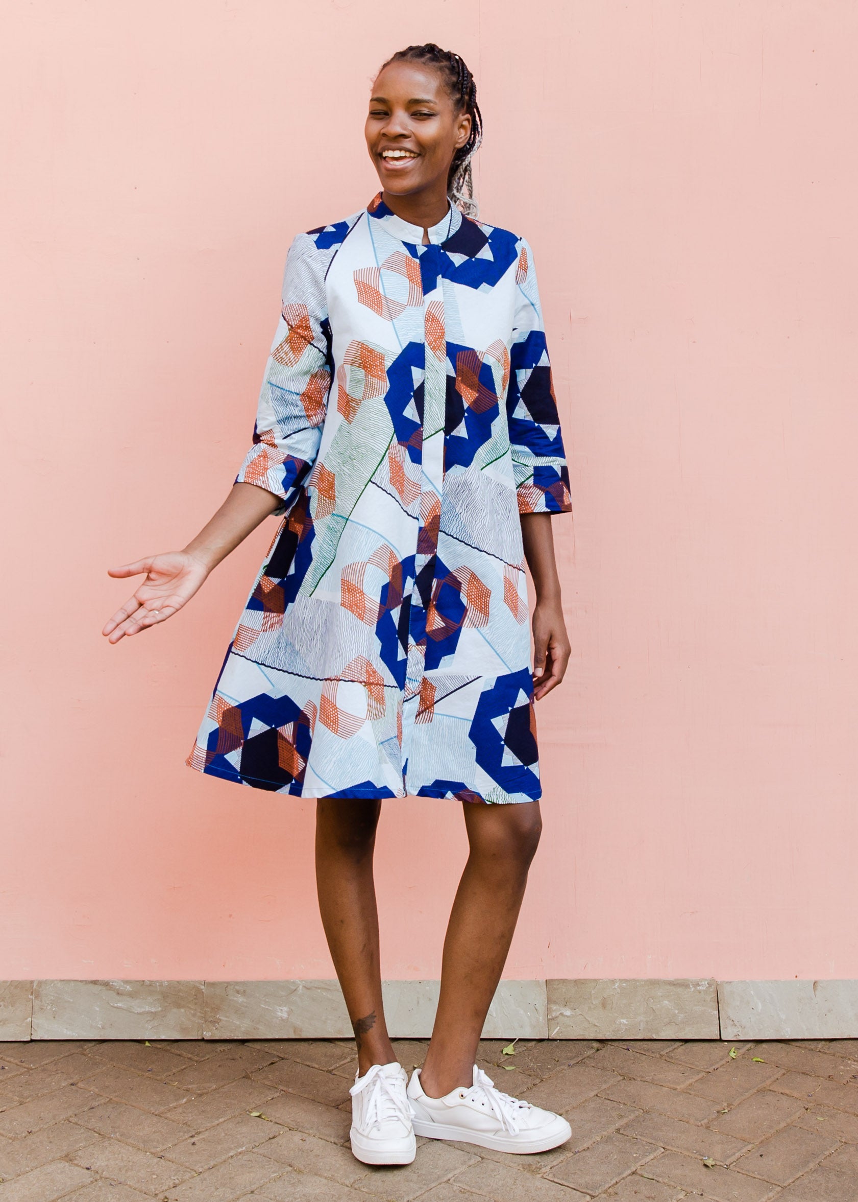 Model wearing dress with blue, green and orange abstract circular design pattern.
