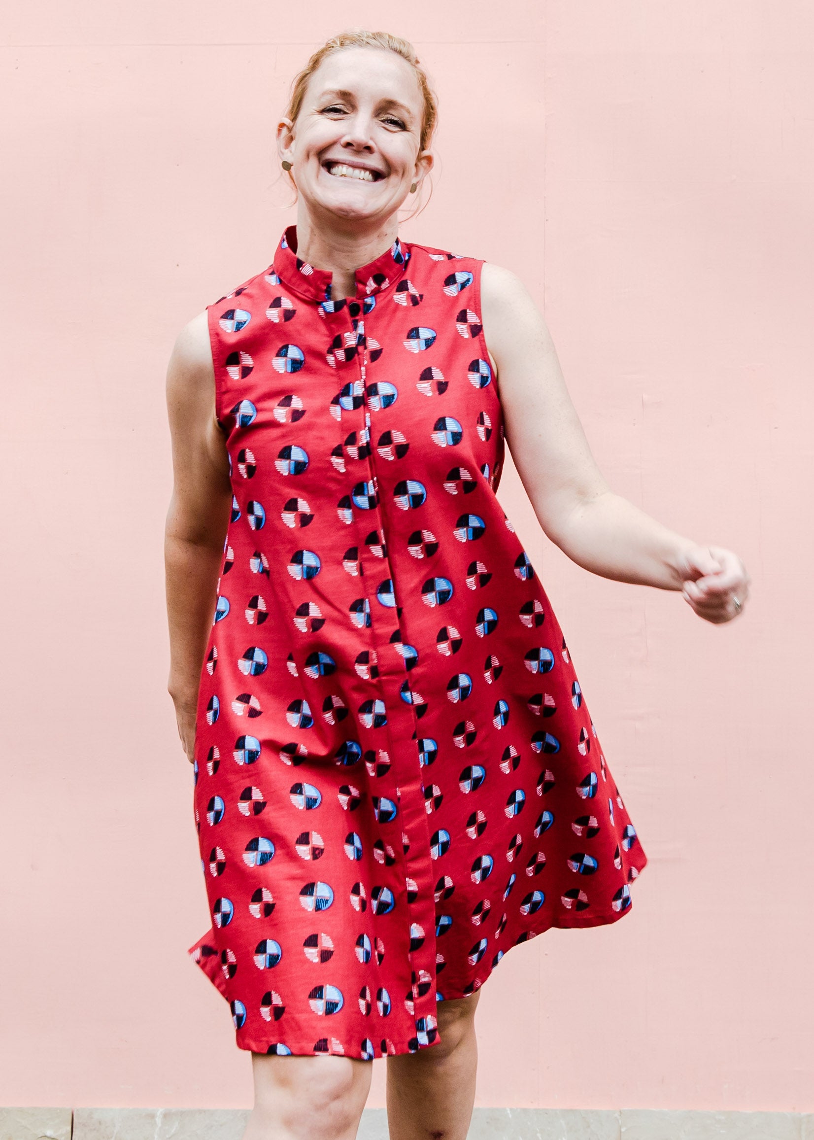 model wearing a sleeveless dress with a red, blue, white and black design