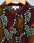 Close up of dress with red, brown and white leaves on black background 