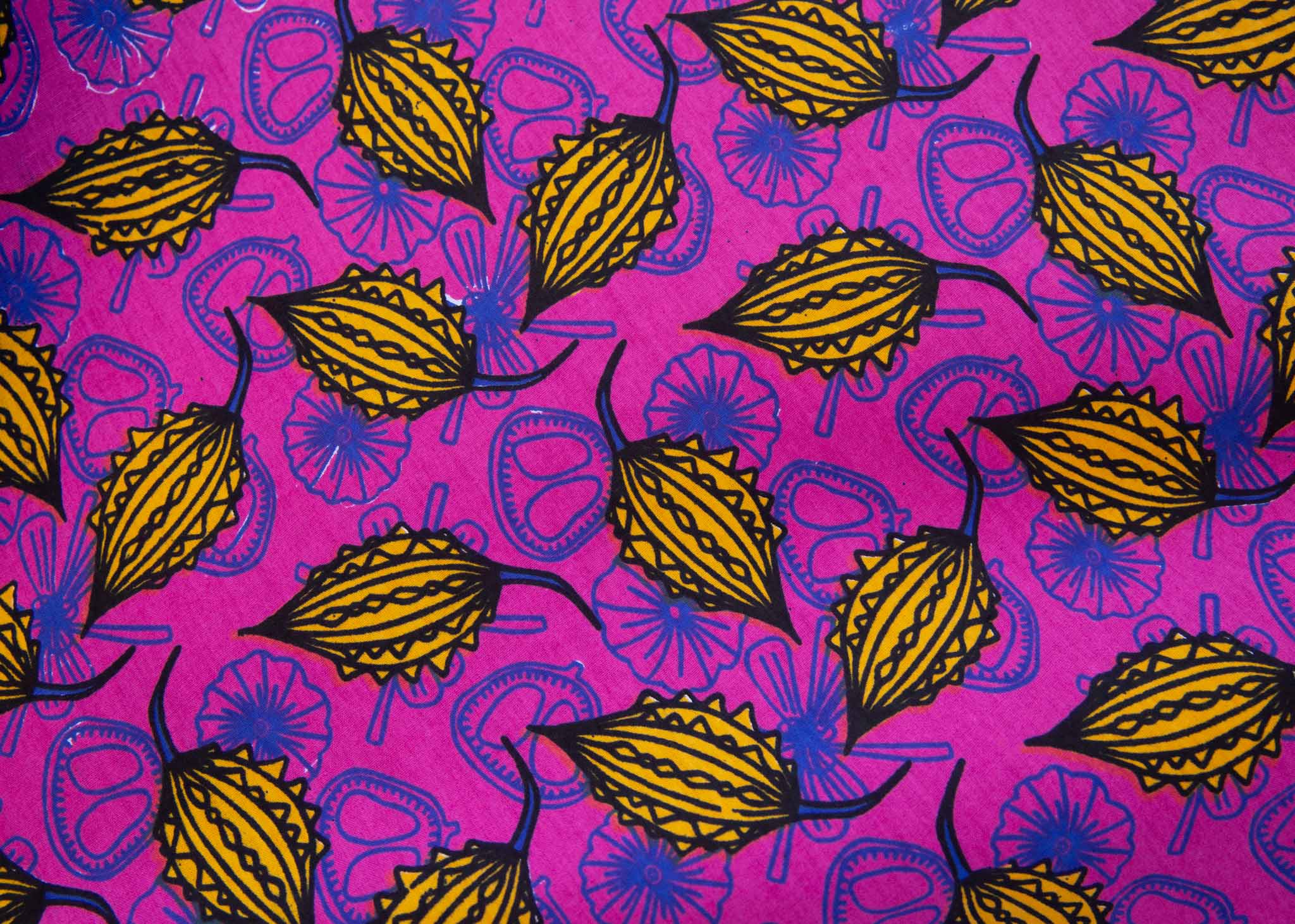 Fabric close up of yellow tamarind design over a pink background.