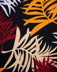 Close up display of black dress with orange, red and white leaf print, fabric.