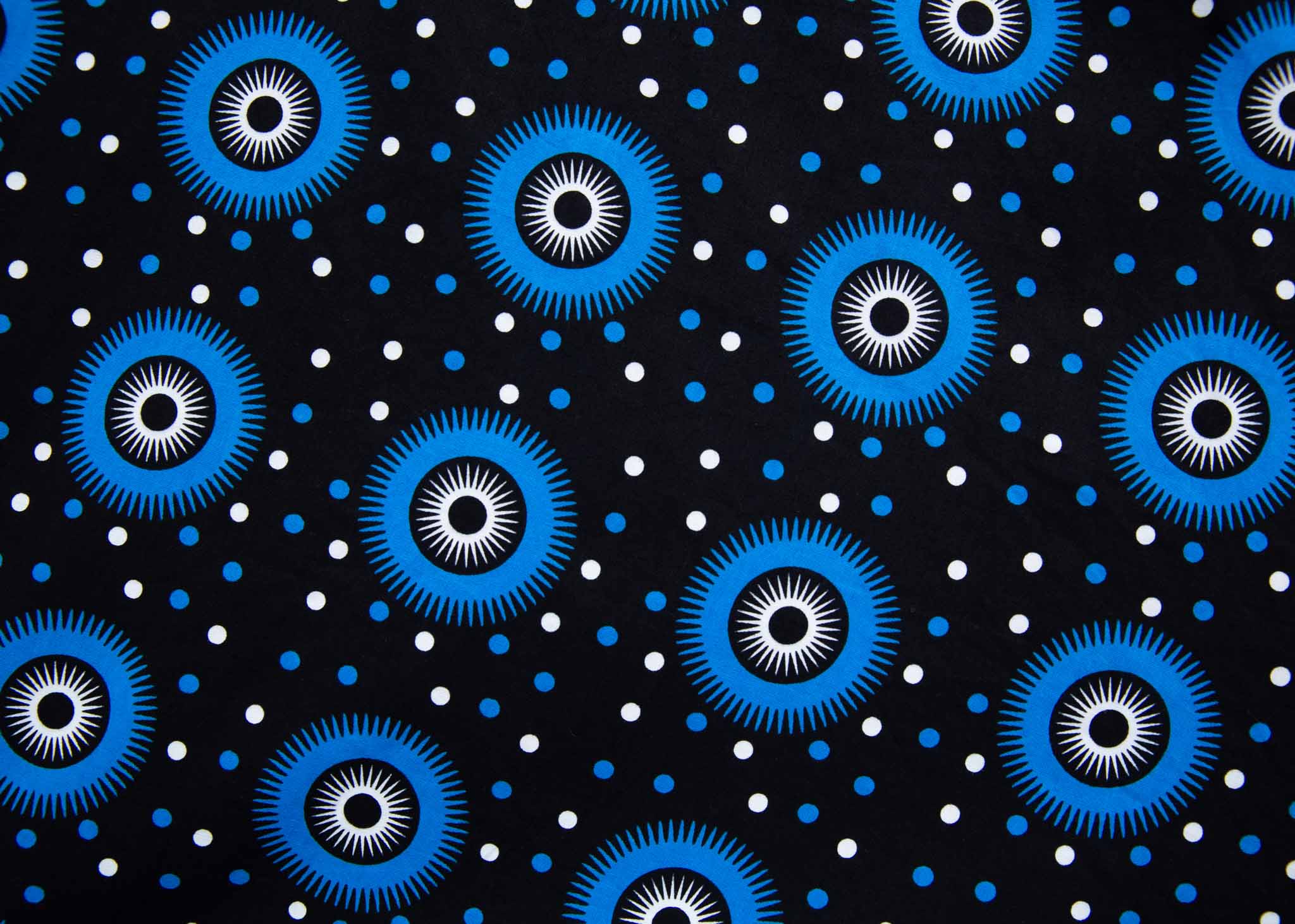 Close up Display of black sleeveless dress with blue and white circle print, fabric.