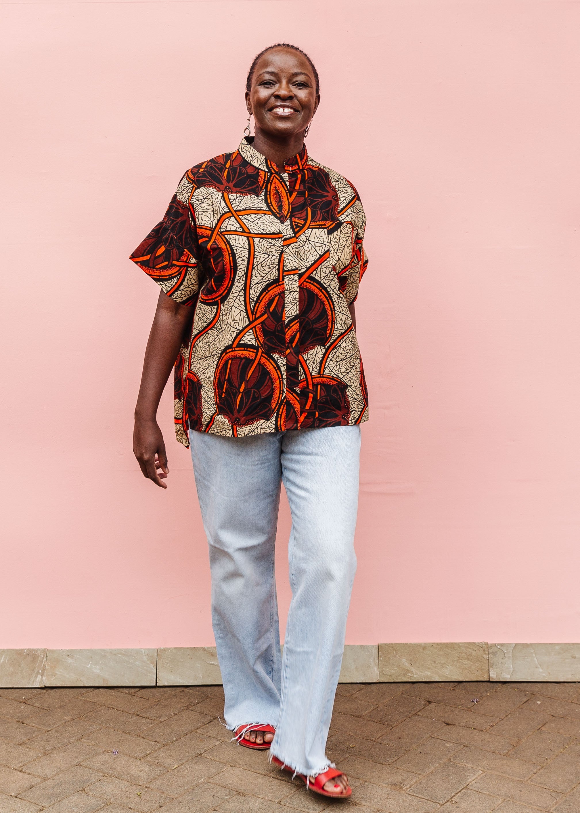 Model wearing beige shirt with brown and orange circles and lines.