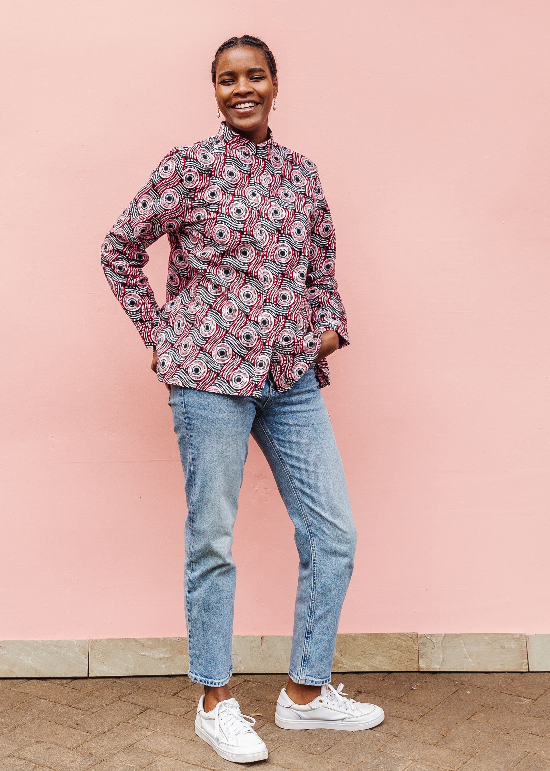 Model wearing long sleeve blouse with black, red, and white circles.