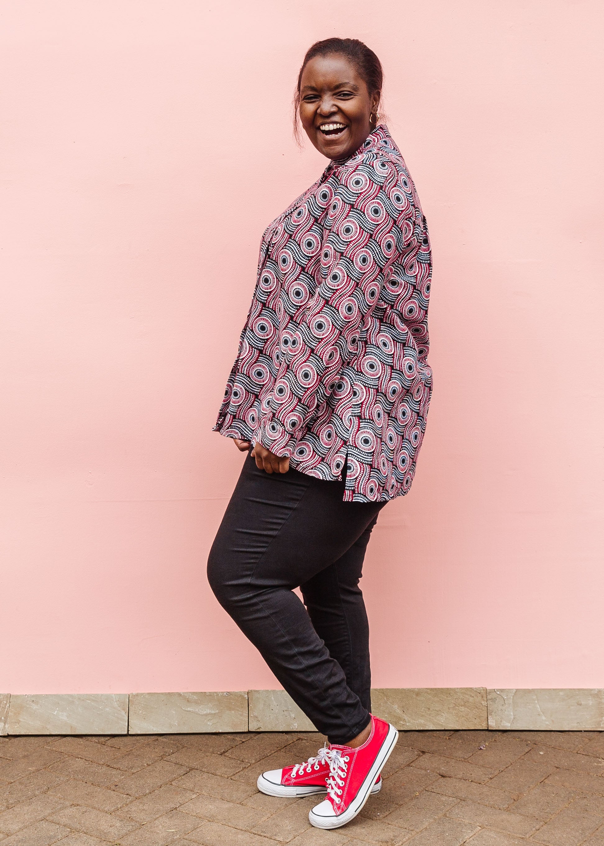 Model wearing long sleeve blouse with black, red, and white circles.