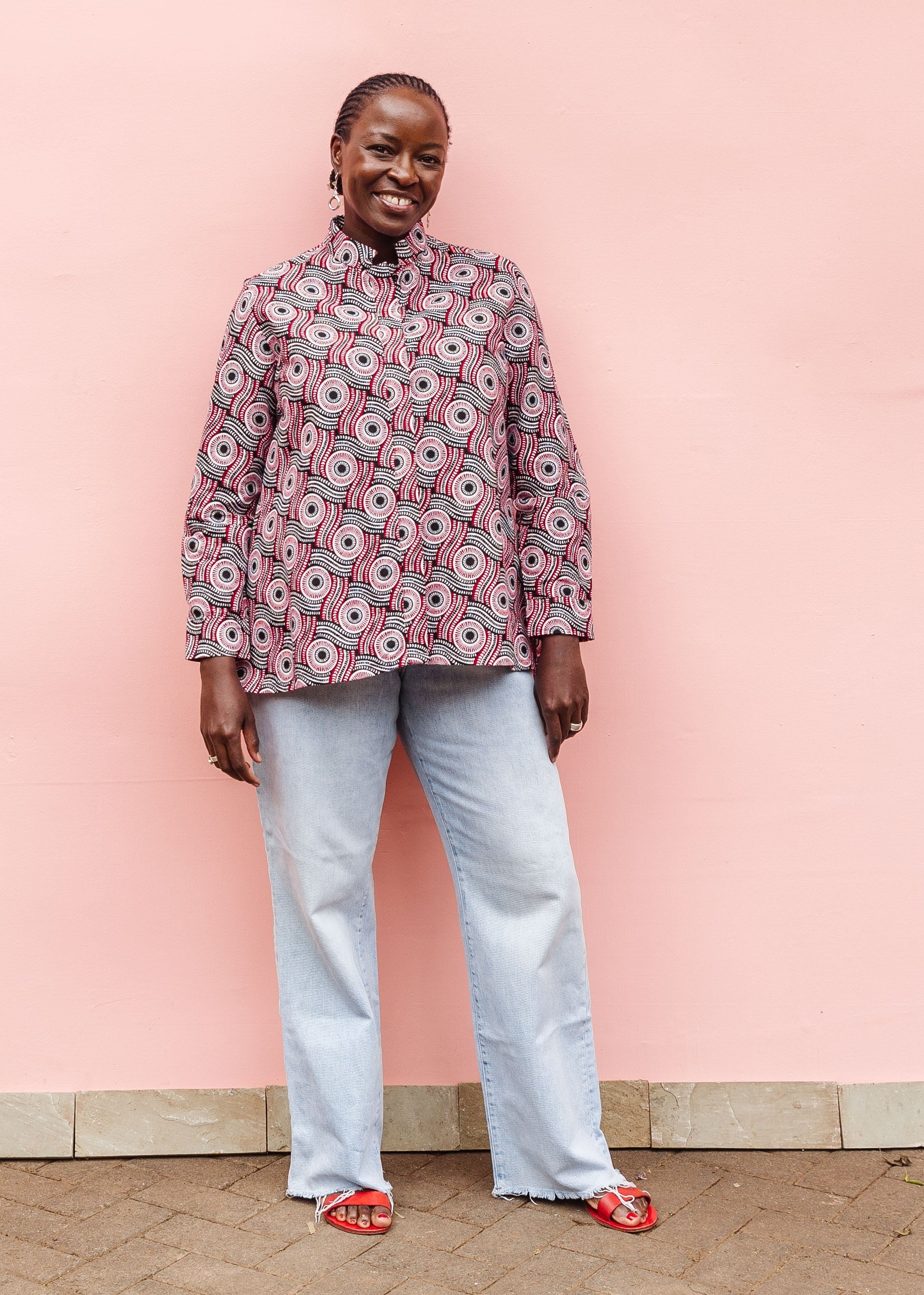 Model wearing long sleeve blouse with black, red, and white circles.