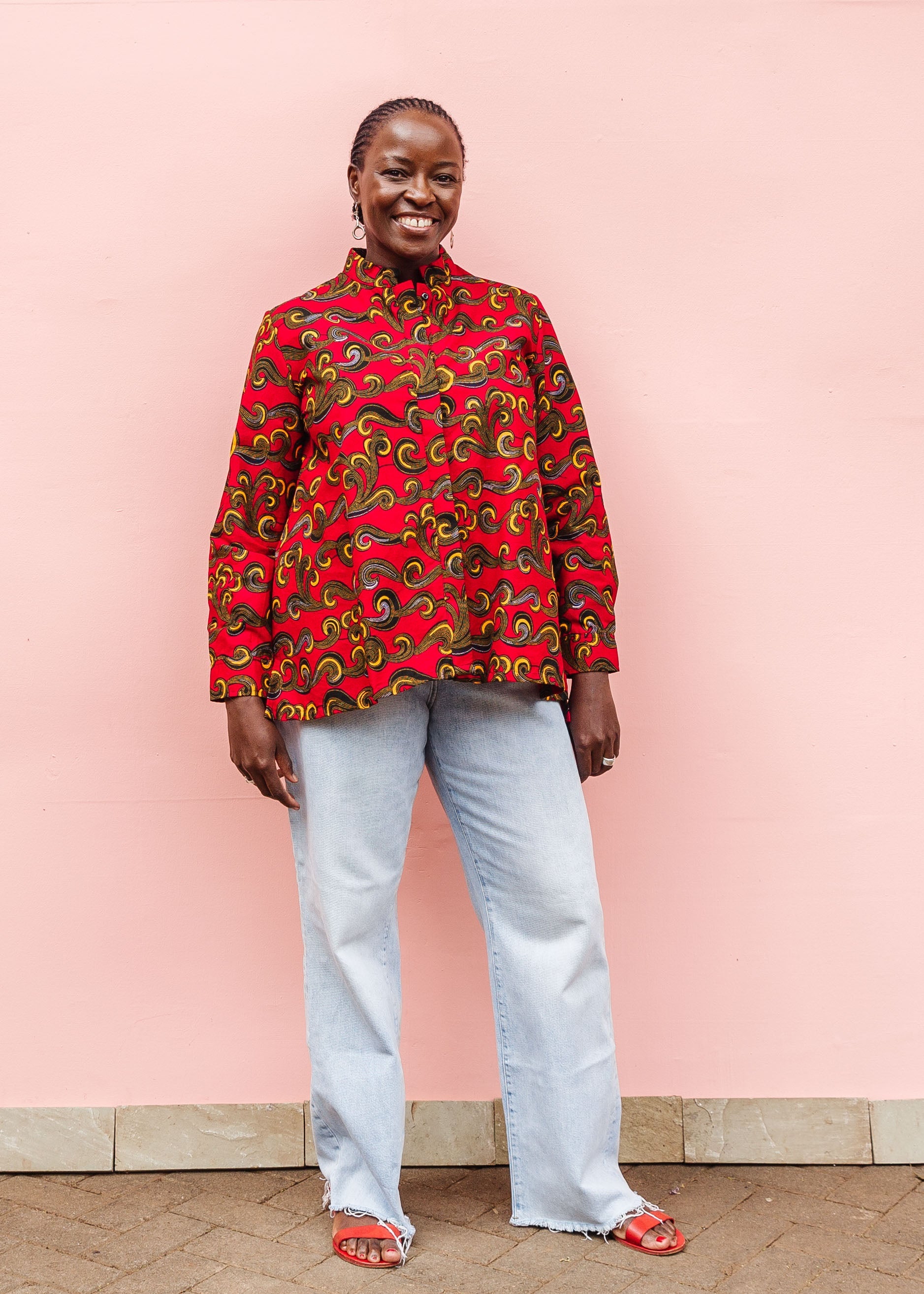 Model wearing red long sleeve blouse with yellow swirls.