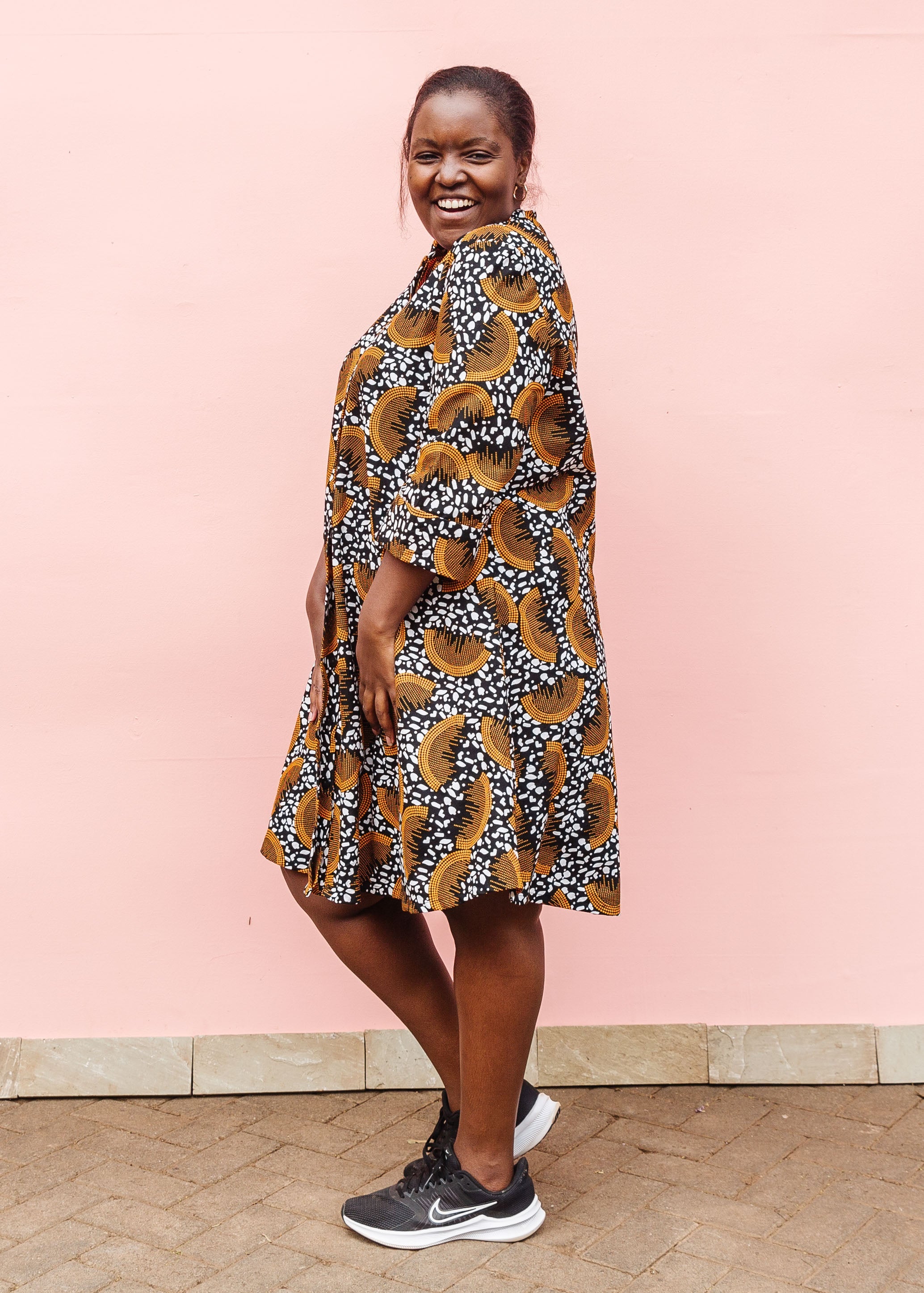 Model wearing black and white dress with orange half circle print.