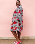 Model wearing dress with large grey and red flower print.