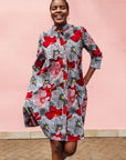 Model wearing dress with large grey and red flower print.