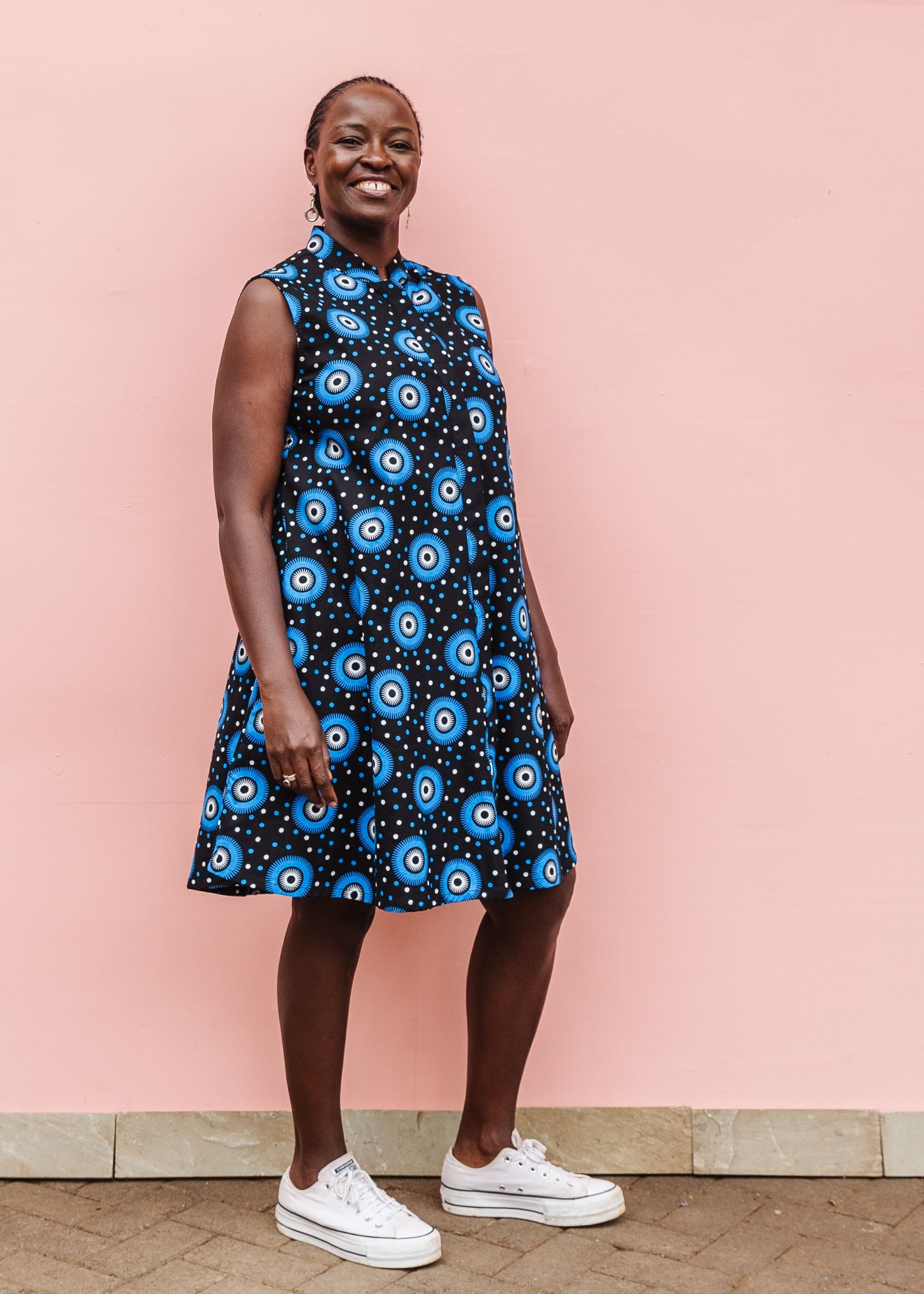 Model wearing black sleeveless dress with blue and white circle print.