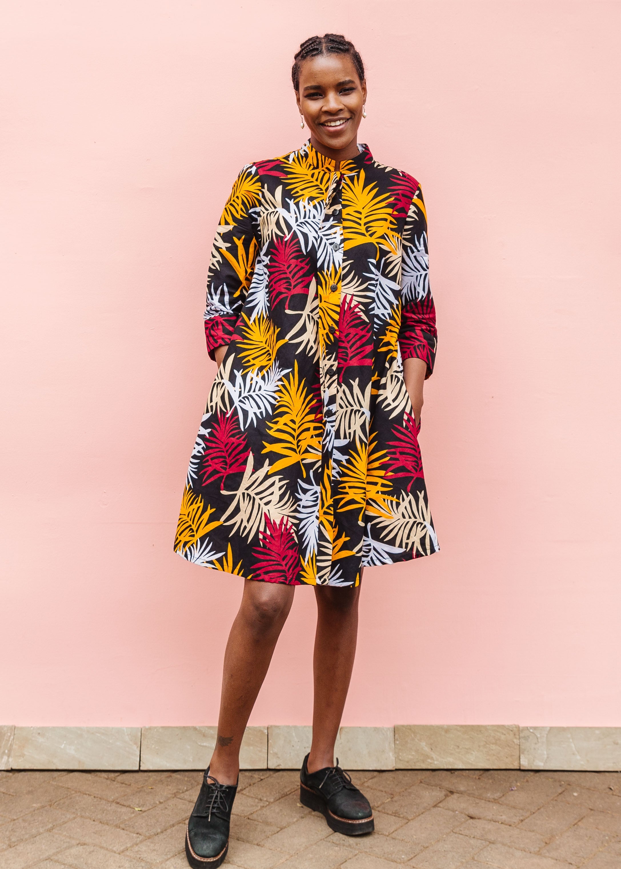 Model wearing black dress with orange, red and white leaf print.