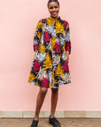 Model wearing black dress with orange, red and white leaf print.