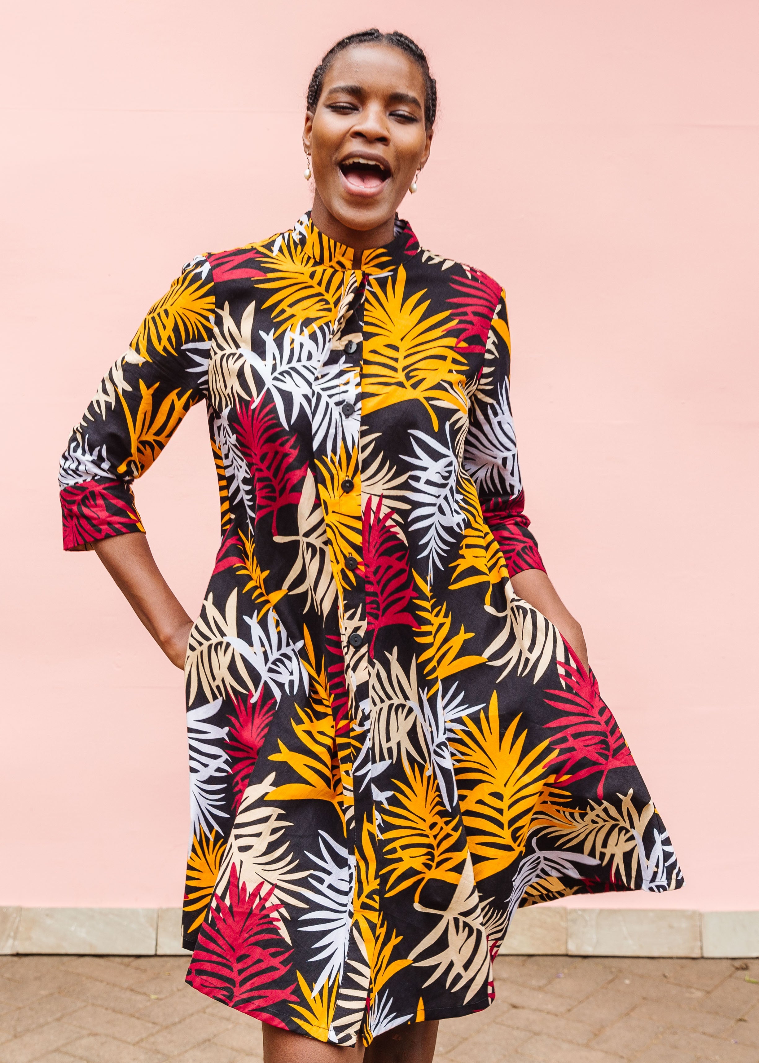 Model wearing black dress with orange, red and white leaf print.