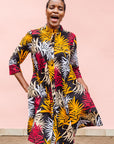 Model wearing black dress with orange, red and white leaf print.