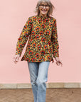 Model wearing mustard long sleeve blouse with red floral print.
