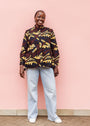 Model wearing long sleeve blouse with brown and yellow abstract print.