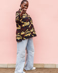 Model wearing long sleeve blouse with brown and yellow abstract print.