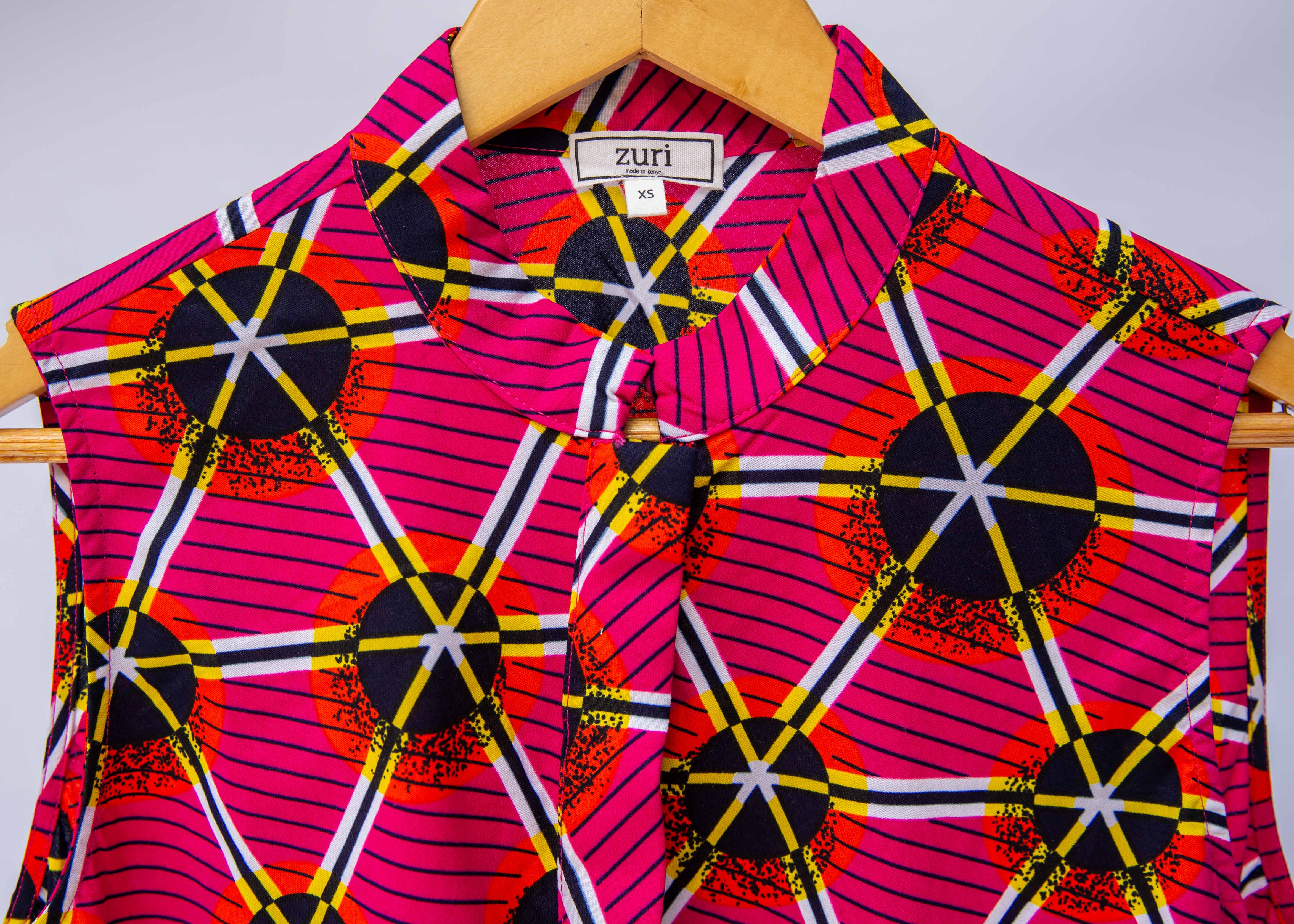 Close up display of fuchsia dress with black dots and white and yellow lines.
