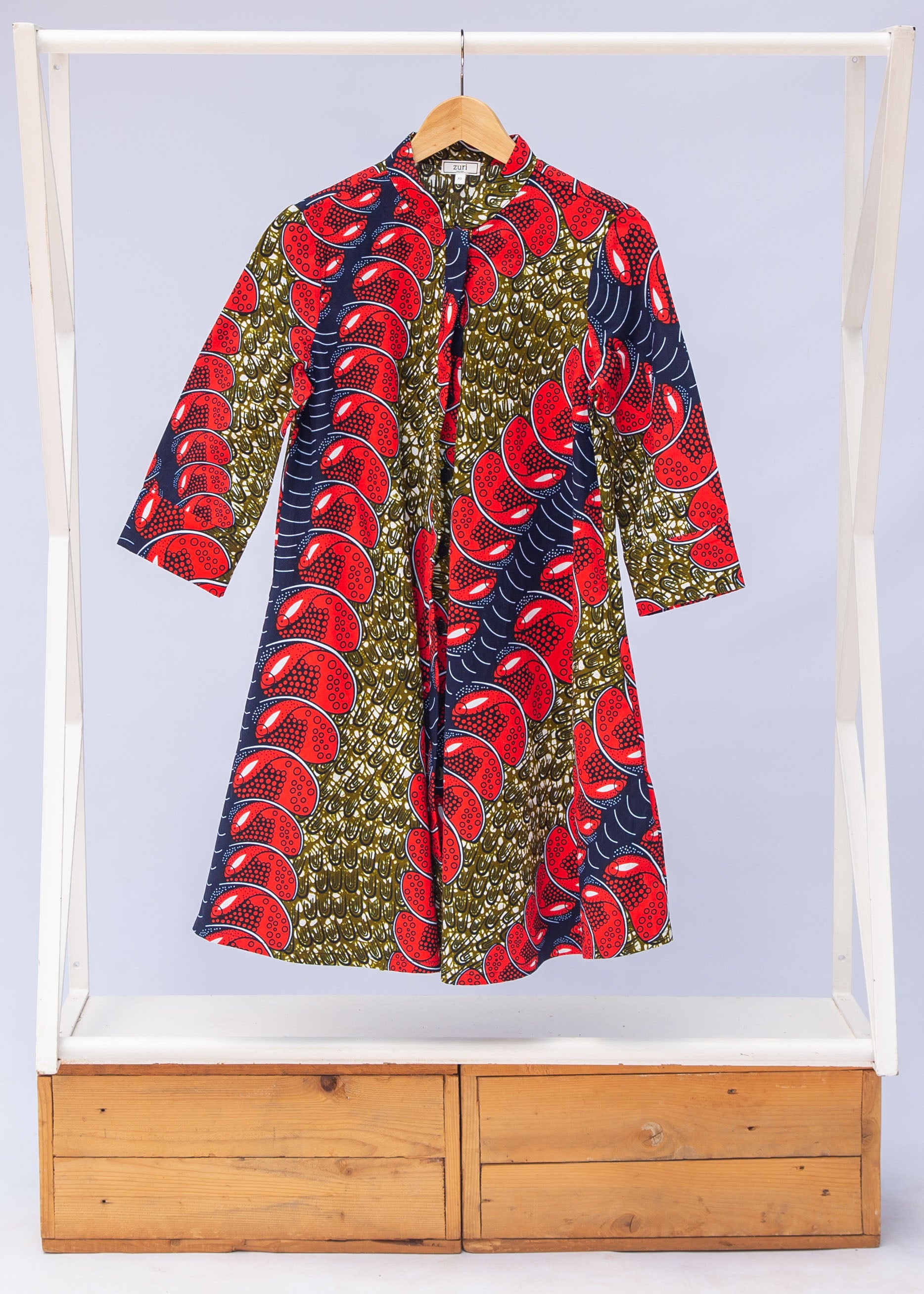 Display of green dress, with bold red and navy bauble print.