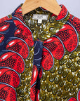 Close up display of green dress, with bold red and navy bauble print.