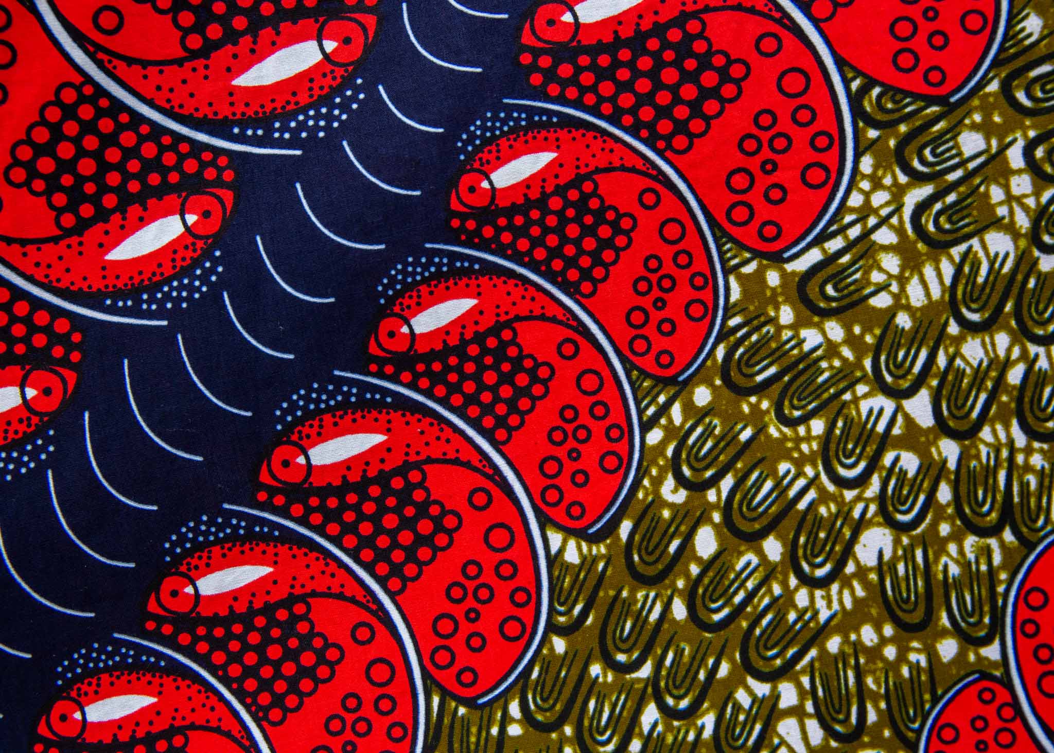 Close up display of green dress, with bold red and navy bauble print, fabric.