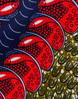 Close up display of green dress, with bold red and navy bauble print, fabric.