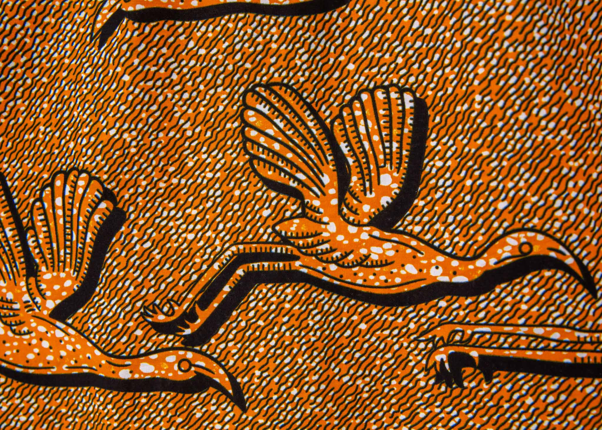 Close up display of golden yellow shirt with flying bird print, fabric.